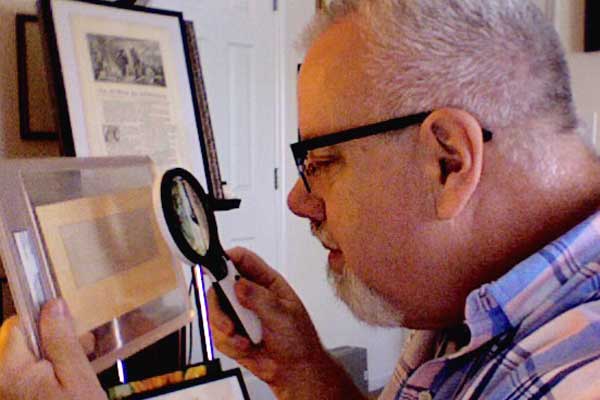 Retired holographer and Wonders of the Bible founder and collector Frank DeFreitas examines the micro handwritten Lords Prayer made by Thomas Edison.