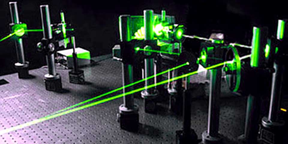 A laser beams travels around an optical table while making a 3D hologram of the Holy Bible.